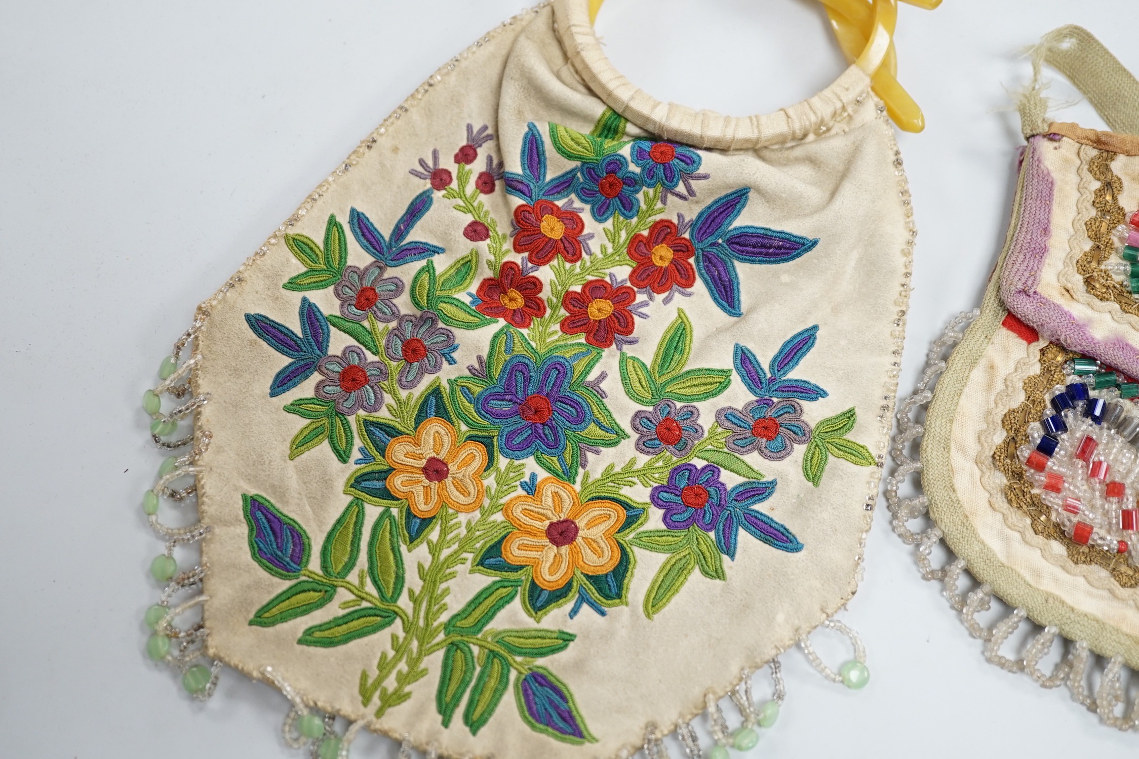 A mid to late 19th century Iroquois, North American/Canadian Indian glass beadwork bag on linen, together with a smaller red wool beaded purse and a 20th century suede embroidered bag with beaded fringe